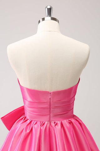 Robe de bal courte plissée rose fuchsia, coupe trapèze, sans bretelles, avec nœud. Adorable robe de soirée courte plissée, sans bretelles, coupe trapèze.