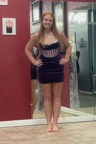 Vestido corto morado sin tirantes, ajustado, con corsé fruncido, ideal para fiestas de bienvenida.