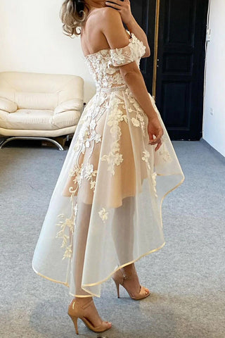 Vestido de fiesta color champán con escote asimétrico, hombros descubiertos y apliques