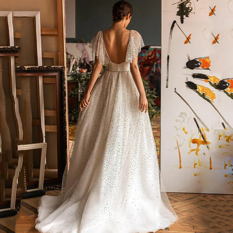 Robe de mariée élégante à paillettes, décolleté cœur, coupe trapèze, manches chauve-souris, dos nu en tulle.