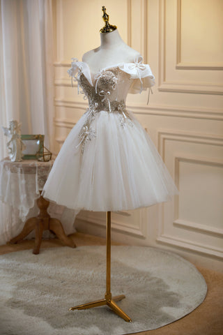 Vestidos cortos de tul con escote en V y hombros descubiertos, estilo chic, ideales para fiestas de bienvenida. 