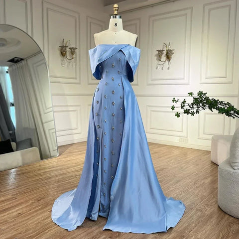 Vestido de noche azul satinado, sencillo y elegante, con escote barco y abertura alta tipo sirena, adornado con cuentas, ideal para fiestas y ocasiones especiales. Modelo LA72458 
