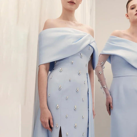 Vestido de noche azul satinado, sencillo y elegante, con escote barco y abertura alta tipo sirena, adornado con cuentas, ideal para fiestas y ocasiones especiales. Modelo LA72458 