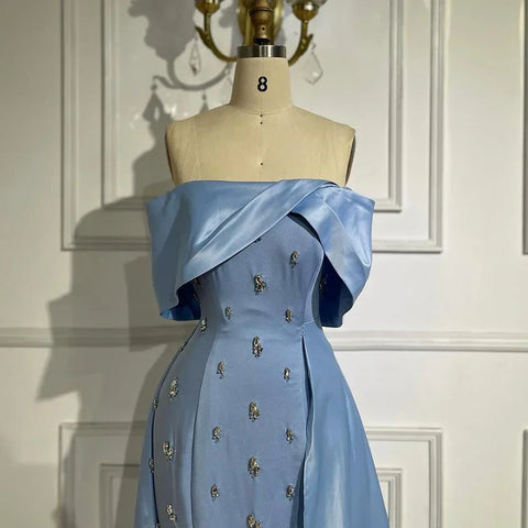 Vestido de noche azul satinado, sencillo y elegante, con escote barco y abertura alta tipo sirena, adornado con cuentas, ideal para fiestas y ocasiones especiales. Modelo LA72458 