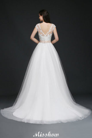 Robe de mariée glamour en tulle, coupe trapèze, décolleté rond et traîne courte, avec ceinture.