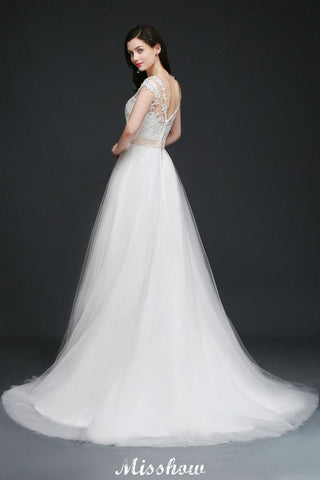 Robe de mariée glamour en tulle, coupe trapèze, décolleté rond et traîne courte, avec ceinture.