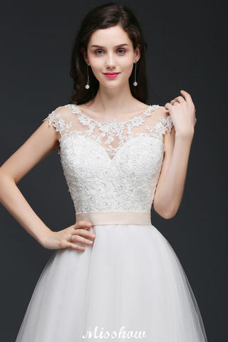 Robe de mariée glamour en tulle, coupe trapèze, décolleté rond et traîne courte, avec ceinture.