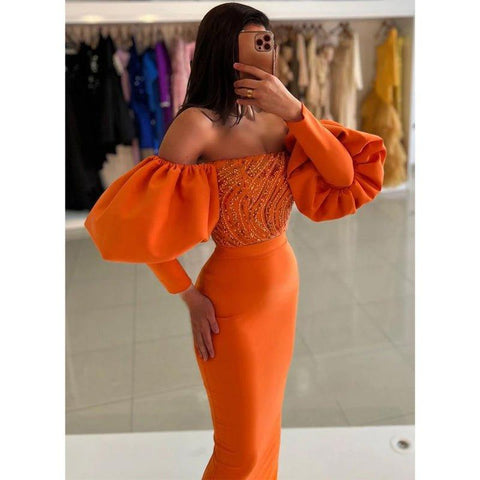 Vestido formal largo, elegante y ajustado, con hombros descubiertos, cuentas y mangas abullonadas en color naranja. 