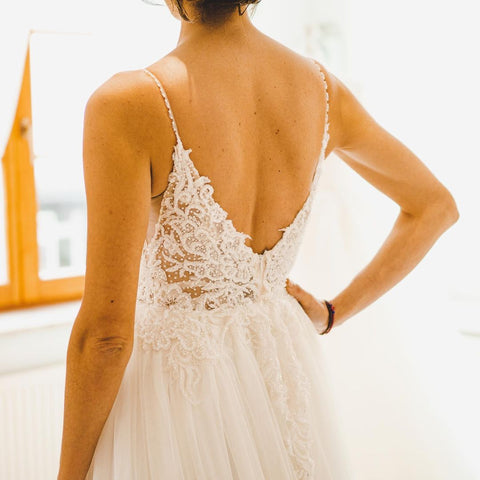 Robe de mariée sobre longue en tulle, coupe trapèze, bretelles spaghetti et dos nu, style A-line.