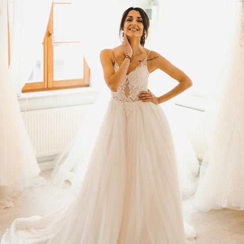 Robe de mariée sobre longue en tulle, coupe trapèze, bretelles spaghetti et dos nu, style A-line.