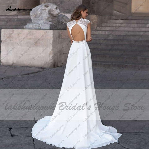 Vestido de novia Abiti Donna Modest Bridal corte A, verano 2025. Sencillo, con escote en V, espalda descubierta, ideal para bodas en la playa. Cola larga.